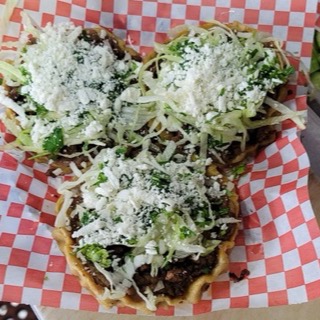 Sopes topped with meat, lettuce and cotija cheese